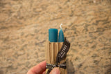 Turquoise beeswax taper candles, one pointed, tied with a Greentree Home ribbon.
