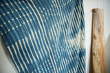 Vintage African indigo textile showing hand-dyed blue stripe pattern with intricate stitched details.