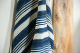 Draped vintage African indigo cotton textile showing handwoven texture and varied blue stripes.