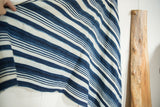 Hand holding vintage African indigo textile, showcasing hand-woven texture and variegated blue stripes.