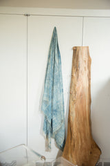 Draped vintage African indigo textile, highlighting variegated blue tones and woven texture with fringe.