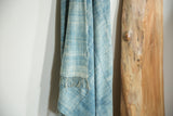 Hand-woven vintage African indigo textile detail: denim blue grid pattern, fringed edge.