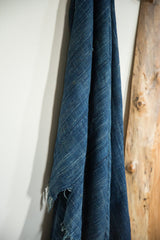 Draped vintage indigo African textile, showing its handwoven texture and frayed bottom edge.