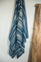 Lower draped vintage African indigo textile, revealing handwoven texture and varied blue stripes.