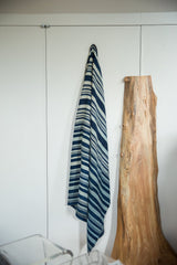 Draped hand woven African indigo textile throw, showcasing varying blue stripes.