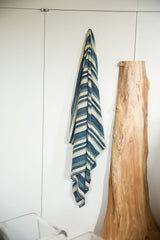 Collectible handwoven African indigo textile, cascading with blue and off-white stripes.