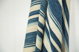 Folded African indigo textile, displaying varied blue and natural cream handwoven stripes.