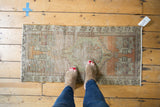 Distressed vintage Oushak runner, low pile with faded terracotta, beige, and sage green patterns.
