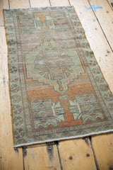 Distressed vintage Oushak rug corner with muted pale terracotta and geometric plant motifs.
