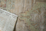 Distressed vintage Oushak rug foundation and textured pile, revealing knot heads, geometric motifs.