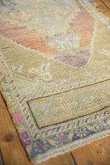 Distressed vintage Oushak rug corner, pale royal blue border with blush and mint motifs.