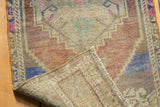 Distressed Oushak rug corner curled back, showing textured pile and hand-knotted foundation.