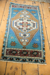 Distressed Oushak rug's corner reveals aqua blue field with aubergine floral vine border.