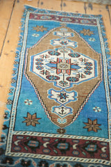 Distressed Oushak rug close-up: aqua blue field, ivory medallion, and aubergine vine border.