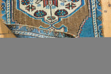 Folded vintage distressed Oushak rug corner, showing blue border, low pile, and hand-knotted edge.