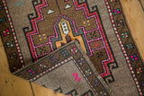 Folded corner of a distressed Oushak rug, revealing its hand knotted foundation and pile texture.