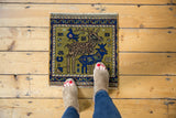Moss green pictorial Oushak rug detail with brown deer, indigo bird, and vine motif.