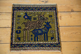 Oushak rug corner showing woven bird, deer, and vine motifs on moss green.