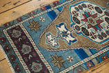 Stepped geometric patterns in aqua blue, aubergine, and earthen bronze on a distressed Oushak rug.