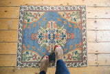 Corner of distressed Turkish Oushak rug, showing sky blue field, beige floral spandrel and border.