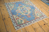 Distressed Turkish Oushak corner with beige floral spandrels, terracotta buds, and sky blue abrashed field.
