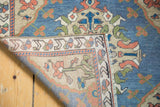 Vintage distressed Oushak rug corner reveals hand-knotted back, low pile, and fringe.