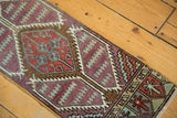 Distressed Oushak runner displaying aubergine, brick red, and mint geometric panel designs.