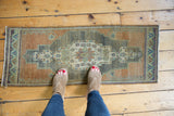 Corner of distressed Oushak rug with blush apricot, time-softened silver tones, and detailed spandrel.