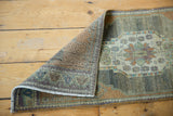 Hand-knotted Oushak rug fold shows distressed pile, faint foundation, and soft colors.