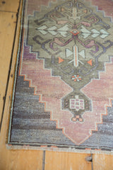 Distressed low pile corner of vintage Oushak rug, showing stepped mauve, aubergine, and silver patterns.