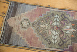 Oushak rug's muted aubergine, blush, and oxidized silver stepped curvilinear motifs.