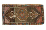 Distressed vintage Oushak rug mat, coffee brown field, with colorful diamond medallion and finials.