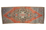 Vintage distressed Oushak rug runner, geometric medallion in brick red, grey, with colorful accents.