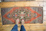 Distressed Oushak runner, rich brick red geometric medallion with subtle floral relief.