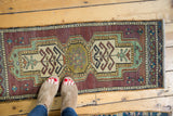 Distressed vintage Oushak runner, elongated medallion, pale aubergine, ivory, and mint green.