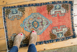 Distressed hand knotted Oushak rug mat, terracotta field with sky blue and ivory serrated motif.