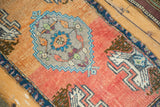 Distressed Oushak rug section with coral field, geometric plant motif in antique ivory and blue.