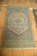 Distressed Oushak rug corner, showing worn pile, muted beige and pale mauve floral patterns.