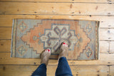 Distressed vintage Oushak rug mat with apricot, silver, and ivory stepped medallion.