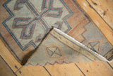 Folded corner of vintage distressed Oushak rug, showing worn pile texture and woven foundation.