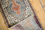 Folded vintage Oushak rug revealing distressed knotting, reverse weave, and secured wine red borders.