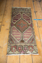 Distressed Oushak rug corner revealing geometric border, aubergine field, and faint foundation wear.
