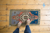 Distressed Oushak rug featuring geometric medallion, terracotta, slate blue fields, and visible knot wear.