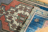 Folded Vintage Distressed Oushak rug mat highlighting worn pile, terracotta, ivory, and sapphire blue patterns.