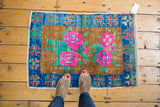Distressed vintage Oushak rug texture with bright pink florals and sapphire blue border.
