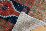 Distressed vintage Oushak rug with worn cherry red, navy geometric pile and woven reverse.