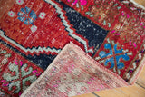 Distressed Oushak rug's cherry red pile and vivid fuchsia accents, revealing hand-knotted foundation.