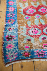Detail of distressed Oushak rug: worn pile exposing foundation, vibrant geometric plum, pink, blue.