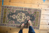 Vintage distressed Oushak rug with ornate medallion, pinwheel motifs, and softened mauve, oxidized silver.