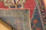 Folded corner of vintage distressed Oushak rug, showing its hand-knotted reverse and red pile.